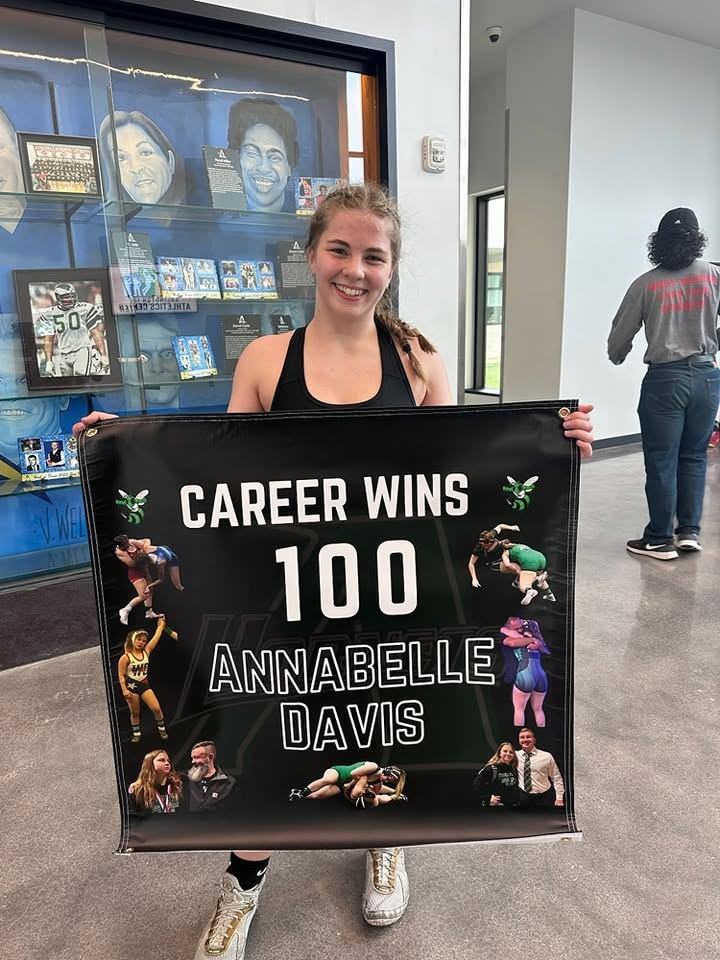 Annabelle Davis holding a 100 career wins banner
