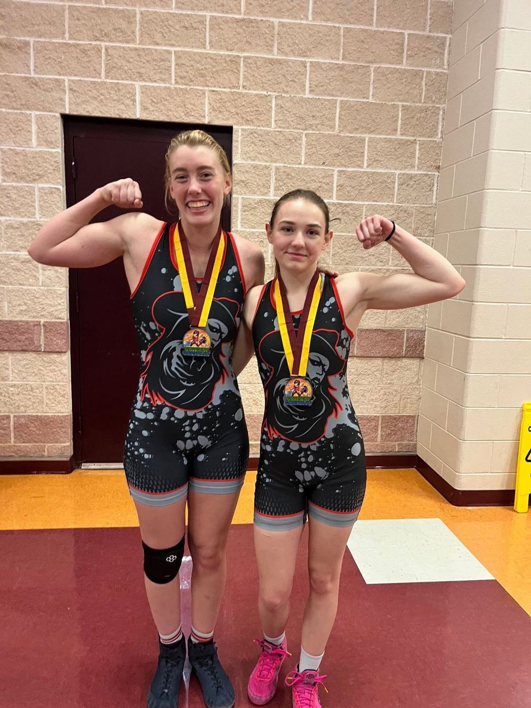Two Texans girls flexing with their medals