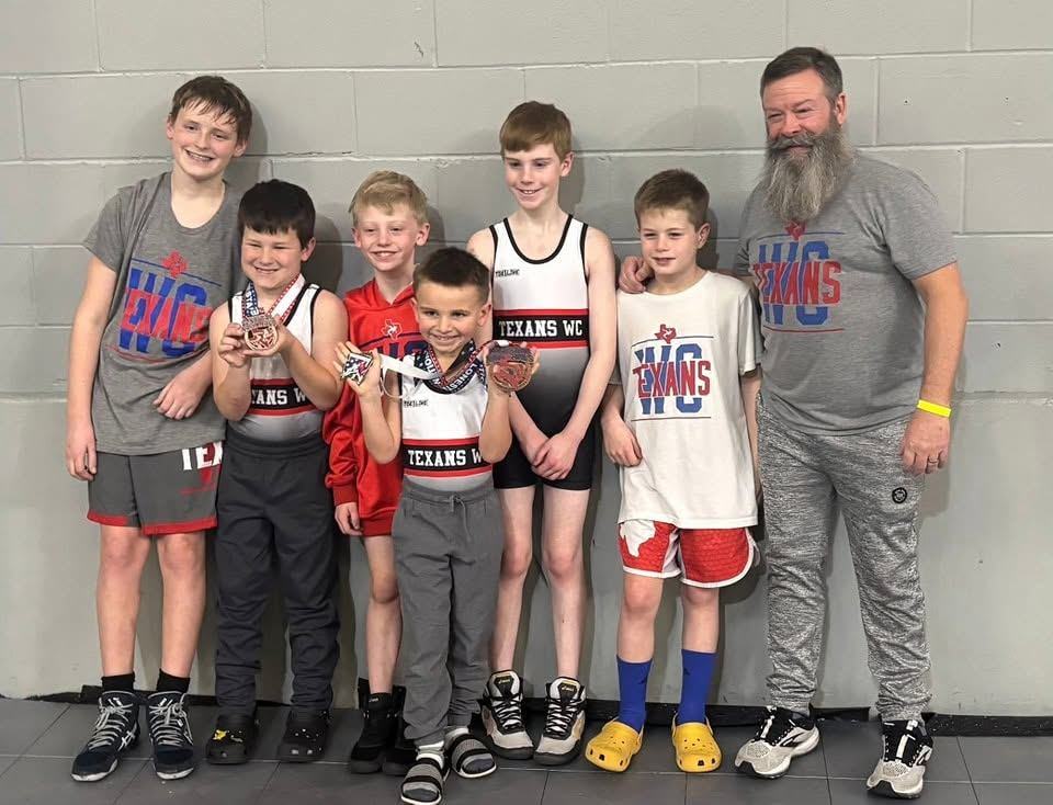 A group of Texans wrestlers with their coach after a tournament
